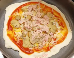 Step <p>Calentamos una sartén antiadherente y doramos la masa a fuego medio-alto.</p><p><br></p><p>Luego le damos la vuelta y vamos al relleno.</p><p>Le echamos un par de cucharadas de tomate frito, queso mozarella, la cuarta parte de los champiñones, la cuarta parte del atún, y espolvoreamos con orégano.</p> illustration